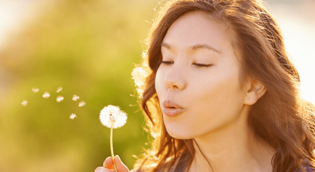 A woman makes a wish on a dandelion.