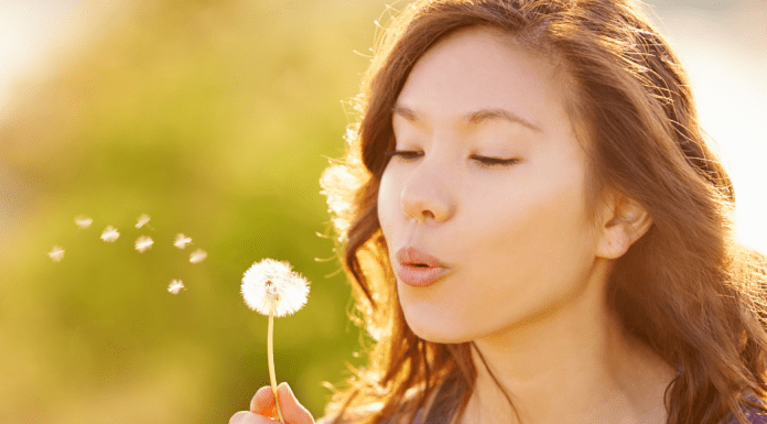 A woman makes a wish on a dandelion.