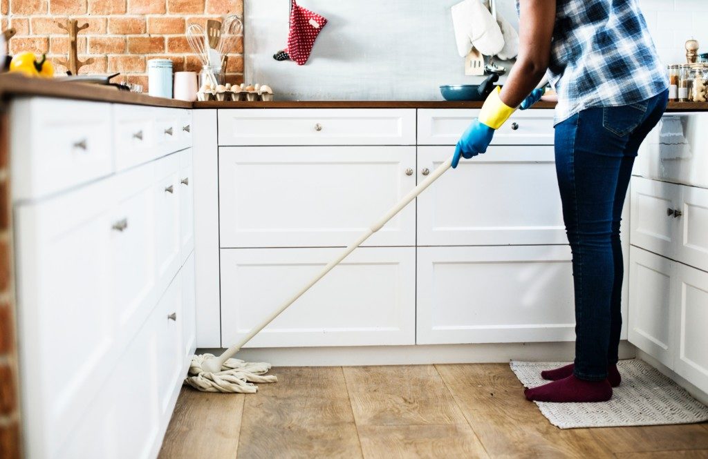 A woman mops the kitchen.