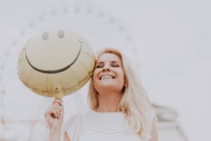 lady smiling next to happy face balloon