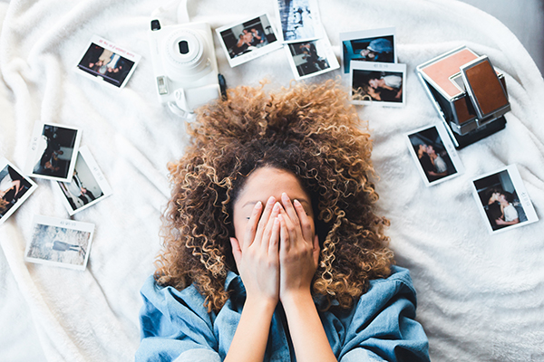 woman laying on bed with pictures and messy hair