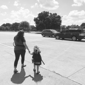 mom holding child's hand in a parking lot. 
