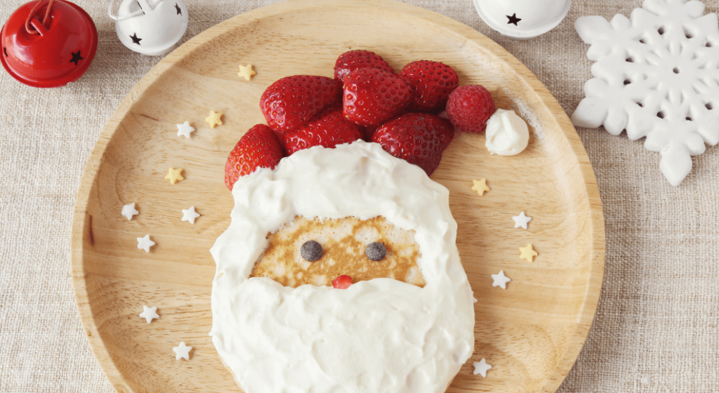 Pancake with strawberries and whipped cream decoration to look like Santa