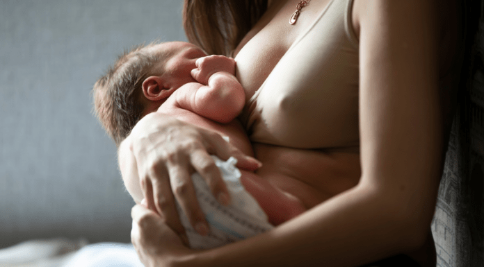 Mother wearing nursing bra is breastfeeding her newborn.