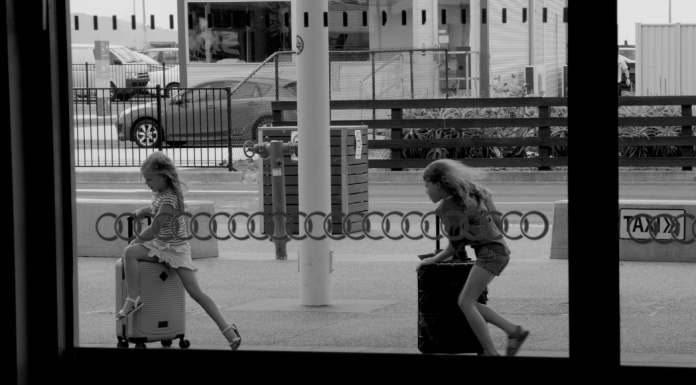 Two girls running through the airport with their suitcases.