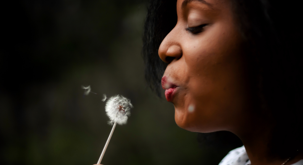 Woman blowing on a flower to make a wish