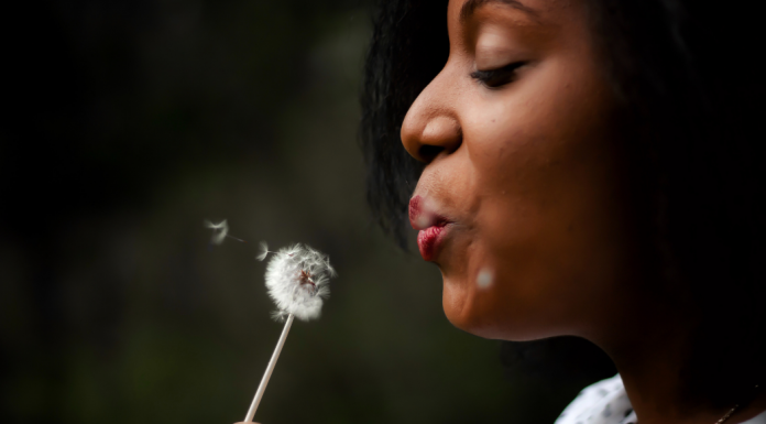 Woman blowing on a flower to make a wish