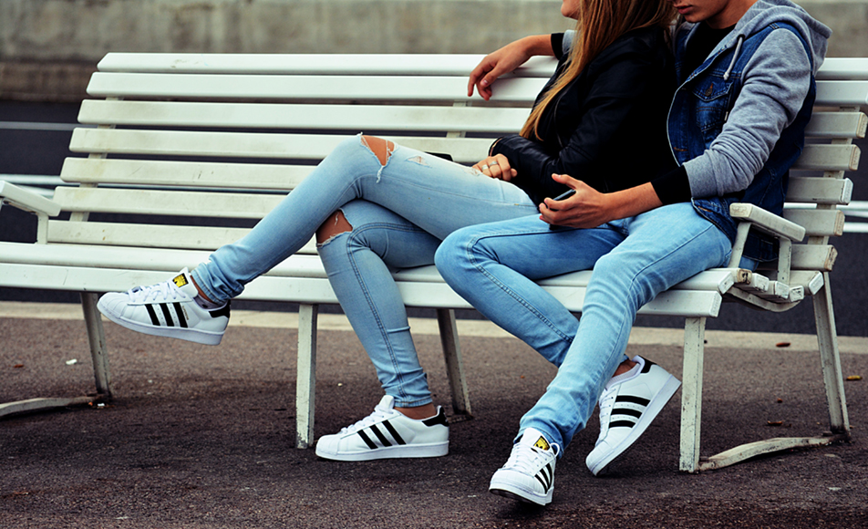 Two teens sitting on a bench.