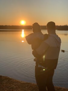 Dad and son looking at the sunset over water.