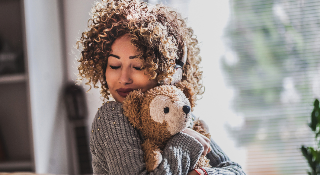 A young woman hugs a teddy bear.