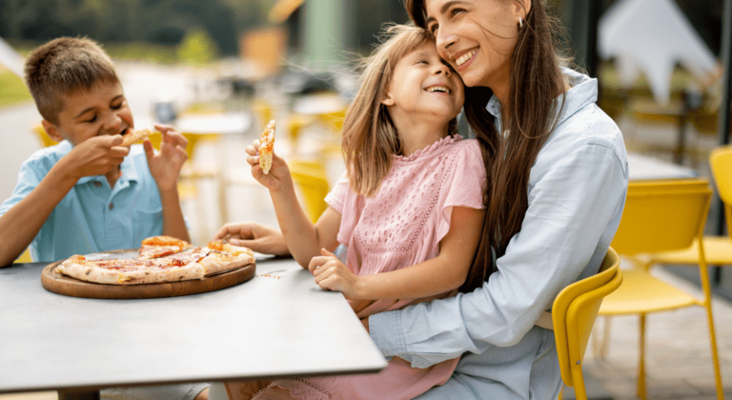 Kids eat pizza with their mom.