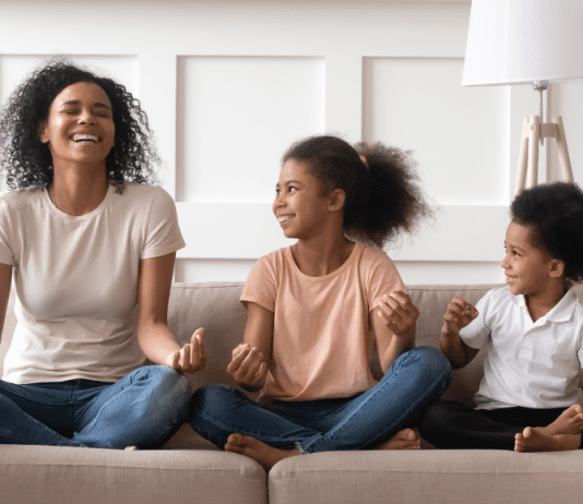 A mom and her kids sit on the couch to meditate.