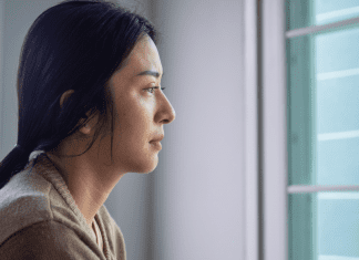 woman looks out the window grieving
