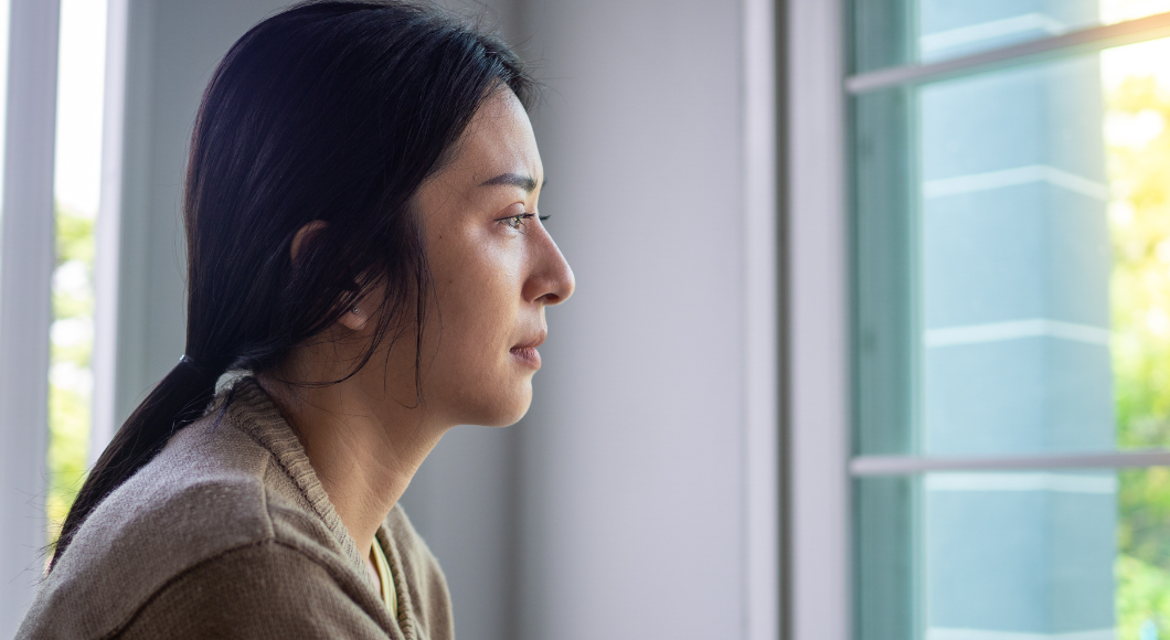 woman looks out the window grieving