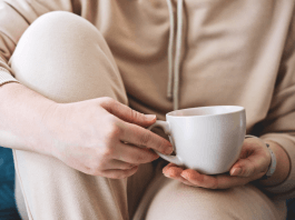 woman in cozy clothes on a couch holding a mug