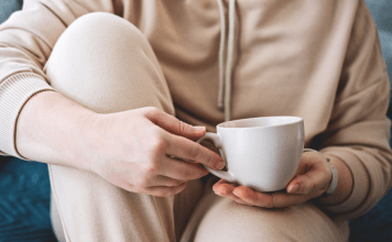 woman in cozy clothes on a couch holding a mug