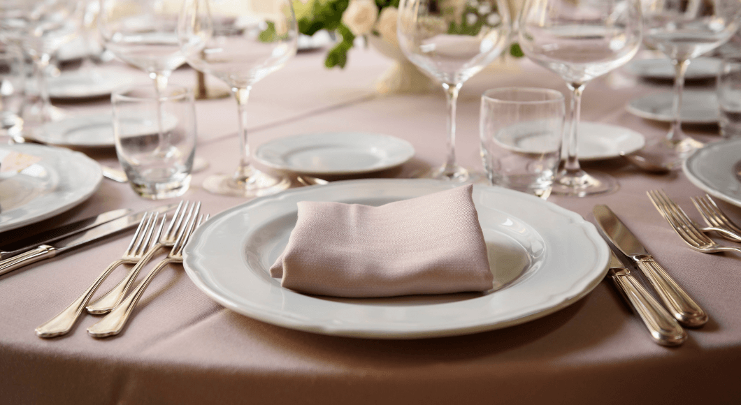 A table is set with plates, silver, and glassware.