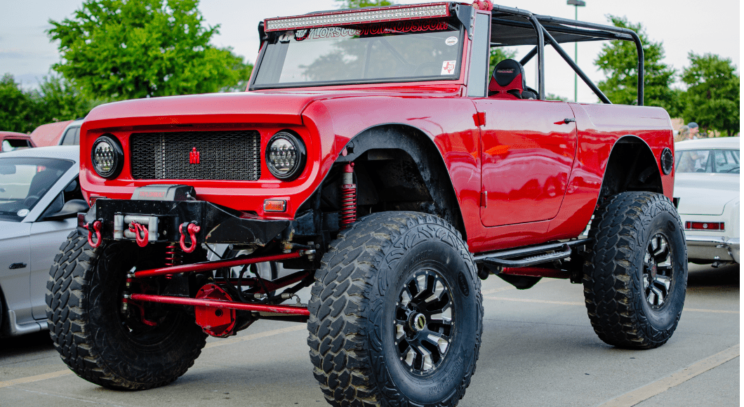 A lifted red truck at a car show.