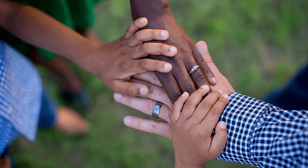 A family of mixed skin tones holds hands.