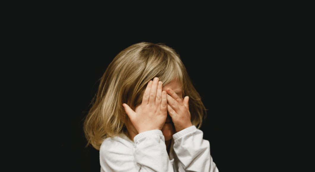 A little girl covers her eyes.