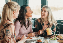 Women sit and laugh over lunch.