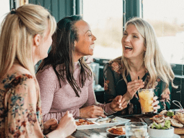 Women sit and laugh over lunch.