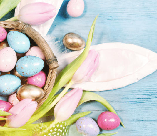 pastel and golden Easter eggs, bunny ears and tulips on a table
