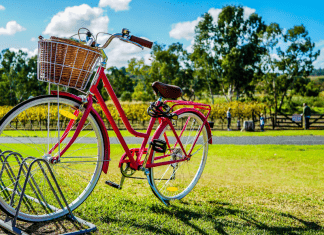 A red bicycle with a basket on the front in a bike rack.