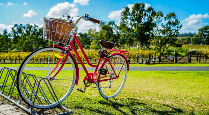 A red bicycle with a basket on the front in a bike rack.