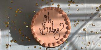 circular terracotta colored cake with '"oh baby'" written on it