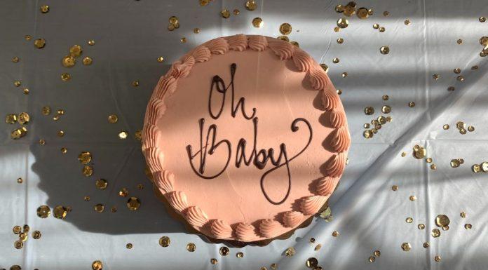 circular terracotta colored cake with 'oh baby' written on it