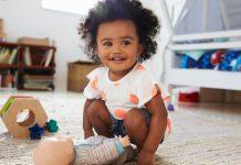 smiling toddler girl playing with a baby doll