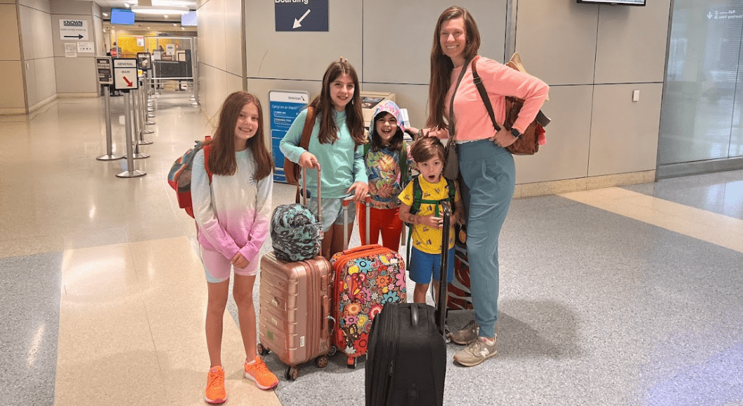 Four children with their mom at an airport getting ready to fly.