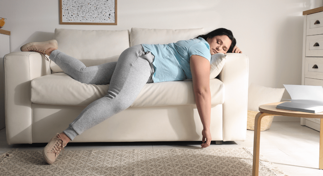 An exhausted woman lays on a couch.