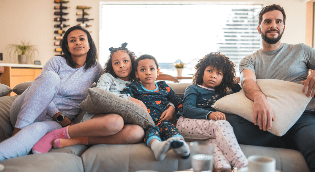 A family lounges on the couch at home in comfortable clothes.