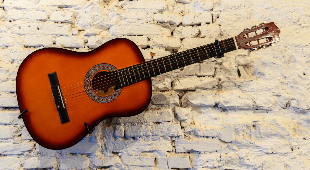 A guitar agains a white brick background.