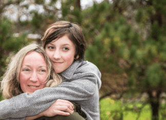 Teenage white daughter with brown hair hugging her older mother with blonde hair