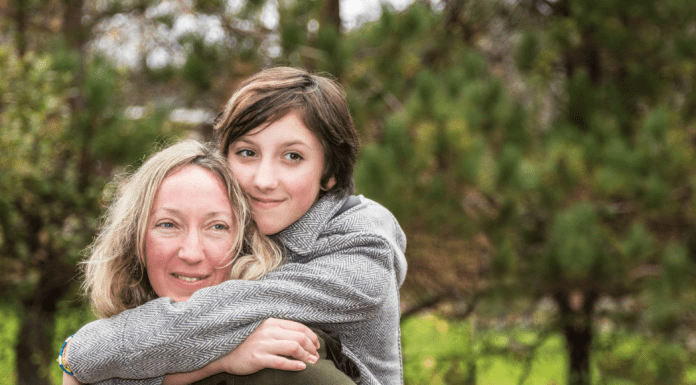 Teenage white daughter with brown hair hugging her older mother with blonde hair