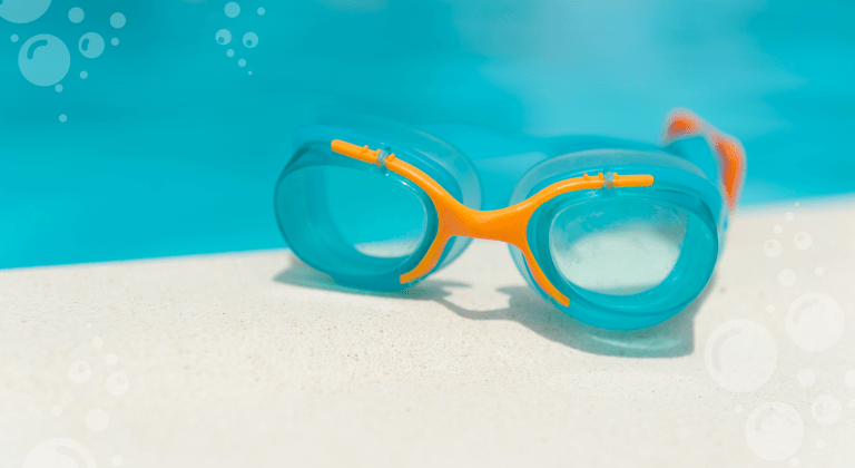 Swim goggles sitting beside a pool