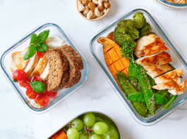 Four bento boxes are filled with roasted chicken, sweet potato, and broccoli plus one with fruit.