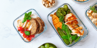 Four bento boxes are filled with roasted chicken, sweet potato, and broccoli plus one with fruit.