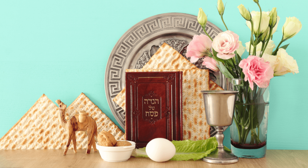 Seder plate, the Haggadah, a wine cup, matzah, and symbolic foods displayed represent Passover.