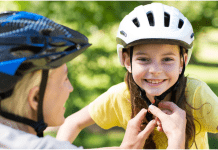 Mother fits a helmet on daughter's head before riding a bike from the bike shop.