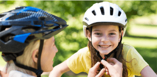 Mother fits a helmet on daughter's head before riding a bike from the bike shop.