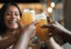 mixed race woman toasts with beers in foreground